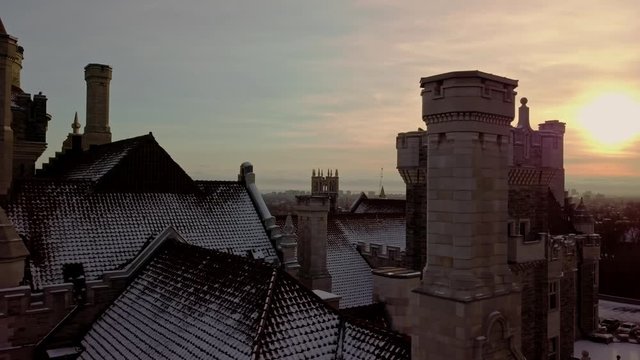 Towers and Tile Roof of a Scenic Castle at Sunset, Drone Slide Right. Aerial parallax truck of Casa Loma Tourist Destination in Toronto Ontario Canada, Winter Golden Light on Unique Old Mansion Home