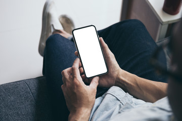 Mockup image blank white screen cell phone.man hand holding texting using mobile on sofa at home.background empty space for advertise text.people contact marketing business,technology
