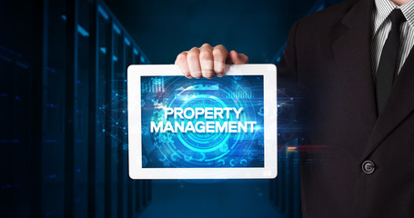 Young business person working on tablet and shows the inscription: PROPERTY MANAGEMENT, business...