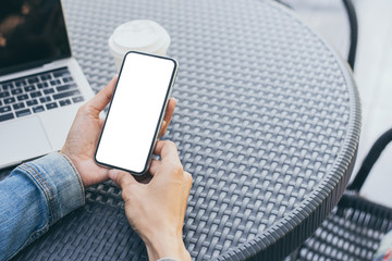 Mockup image blank white screen cell phone.man hand holding texting using mobile on desk at coffee shop.background empty space for advertise text.people contact marketing business,technology