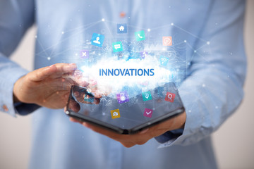 Businessman holding a foldable smartphone with INNOVATIONS inscription, technology concept