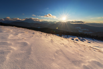 Charming snow-capped houses on a mountain Carpathian mountain valley, with magnificent views of peaks in winter.