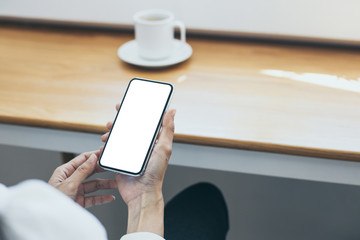 Mockup image blank white screen cell phone.man hand holding texting using mobile on desk at coffee shop.background empty space for advertise text.people contact marketing business,technology