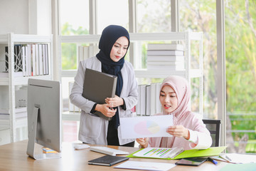  Two Muslim women are involved in business work with in the office.