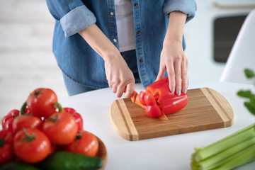 Obraz na płótnie Canvas Female hands with knife cutting slice of red pepper.