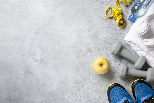 Fitness background with dumbbells, sneakers, towel, headphones and water bottle
