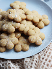 flower-shaped gingerbread cookies lie on a plate on a dirty gray table