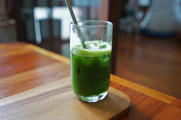 Close up glass of Iced Matcha green tea on wooden tray table