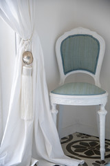 Interno camera da letto, sedia. Stile moderno e antico si mescolano tra loro.