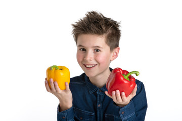 Junge mit Gemüsepaprika, rot und gelb, in den Händen, freigestellt, Hintergrund weiß