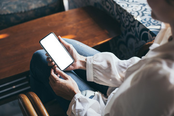 Mockup image blank white screen cell phone.woman hand holding texting using mobile on desk at coffee shop.background empty space for advertise text.people contact marketing business,technology