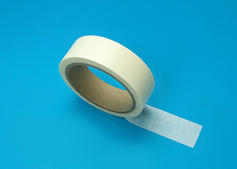 Round roll of white duct tape, adhesive tape on a blue background