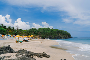 Virgin beach in Bali with sun beds boats and white sand. The Paradise place in Bali. Blue sea and...