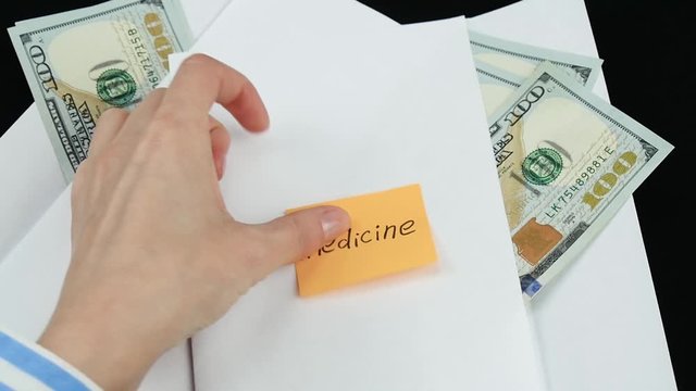 Envelopes with money on lie on the table. The hand of an unknown person sticks a sticker with the words "medicine" on an envelope with money. The concept of paying bills, savings, and personal finance