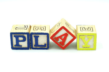 The word Play spelled in colorful wooden blocks, isolated on white background