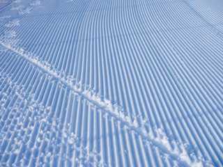 Snowcat tracks in the snow. The stripes form an amazing snowy texture. Theme of relaxation in a ski resort