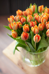 Huge spring bouquet of tulips on a wooden table. Beautiful flowers composition in orange and yellow colors. Perfectly for Women's Day. Copy space. Top view.