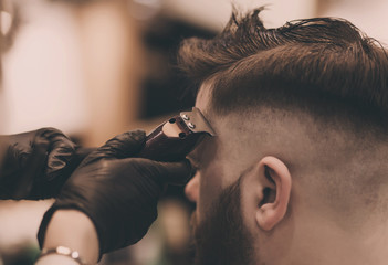 Confident bearded man visiting hairstylist in barber shop