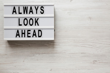 'Always look ahead' words on a modern board on a white wooden surface, top view. Overhead, from above, flat lay. Copy space.