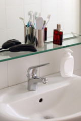 bathroom sink with body care equipment on a glass shelf with copy space for your text