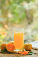 A glass of orange juice and citrus fruits on a wooden table