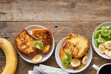 French toasts with kiwi and banana on a wooden background 