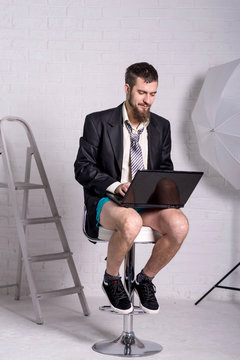 Man in a jacket and shorts is sitting with a laptop, the concept of remote work.