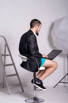 Man in a jacket and shorts is sitting with a laptop, the concept of remote work.