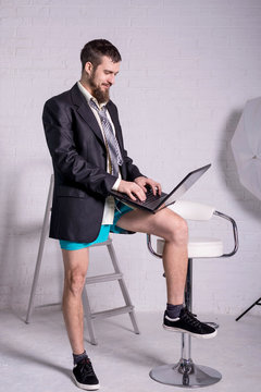 Business man in a jacket and shorts working on the laptop remotely.