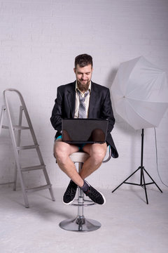 Man in a jacket and shorts is sitting with a laptop, the concept of remote work.