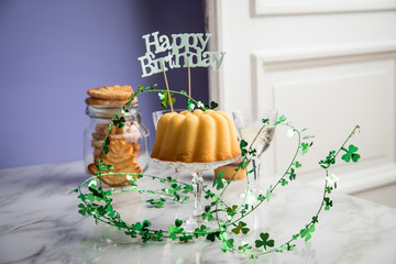 Geburtstagsfeier mit Gugelhupf Kuchen, Muffins, Kekse Gebäck und Sekt mit Happy Birthday Dekoration und Kleeblättern zum Geburtstag