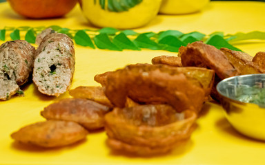 Close up shot of indian deep fried onion rings and lamb kebab with mint and herb chutney on a bright yellow chopping board.