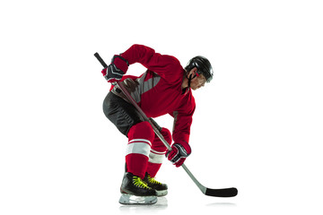 Activity. Male hockey player with the stick on ice court and white background. Sportsman wearing...