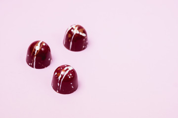 Three Luxury Bonbons Painted with White Colors on Pink background Beautiful and Exclusive Handmade chocolate Candy Horizontal Copy Space