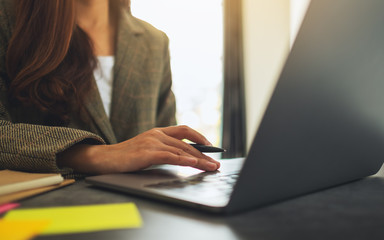 Closeup image of a businesswoman using and typing on laptop computer with paperwork on the table in office