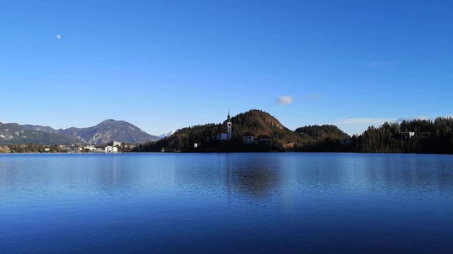 Wide shot lake Bled island Catholic church with waves on water surface, Slovenia