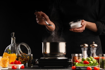 The chef cooks a soup with vegetables. Salts, freezing in motion. Culinary and cooking. Delicious and proper nutrition. Gastronomy, restaurant business or hotel business.