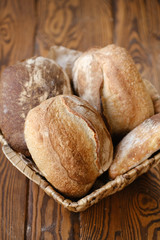 Assortment of baked bread on wooden table background. Bread background, top view of white, black and rye loaves. Healthy food. 