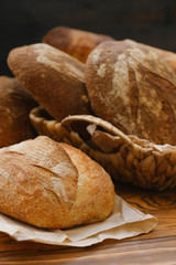 Assortment of baked bread on wooden table background. Bread background, top view of white, black and rye loaves. Healthy food. 