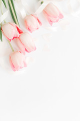 Happy womens day. Pink tulips with ribbon and hearts on white background, flat lay. Stylish soft vertical image. Greeting card mockup with space for text. Happy Mothers day. Valentines day