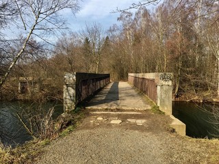 Cemento iron concrete bridge leading over pond to small forest