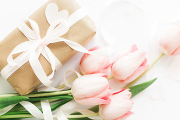Pink tulips flat lay with ribbon and gift box on white background. Stylish soft image of spring flowers. Happy womens day. Greeting card mockup. Happy Mothers day. Hello spring