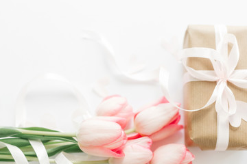Pink tulips with ribbon and gift box on white background. Space for text. Stylish soft image of spring flowers. Happy womens day. Greeting card mockup. Happy Mothers day. Hello spring