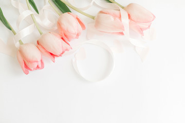 Hello spring. Pink tulips with ribbon and hearts on white background, flat lay. Stylish soft spring image. Happy womens day. Greeting card mockup with space for text. Happy Mothers day.
