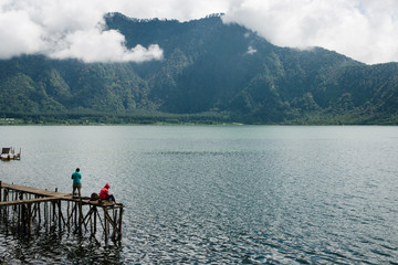 Dos personas contemplando el lago y Bratan en Bali con montañas de fondo