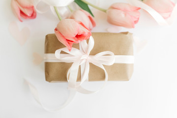 Pink tulips flat lay with ribbon and gift box on white background. Stylish soft image of spring flowers. Happy womens day. Greeting card mockup. Happy Mothers day. Hello spring