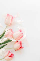 Fototapeta premium Pink tulips with ribbon and hearts on white background, flat lay. Stylish soft vertical image. Happy womens day. Greeting card mockup with space for text. Happy Mothers day. Valentines day