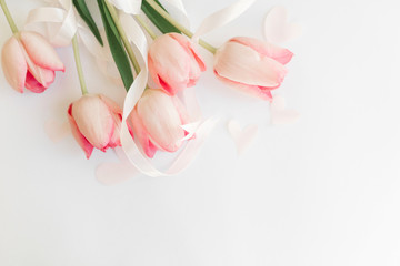 Pink tulips with ribbon and hearts on white background, flat lay. Stylish soft spring image. Happy...