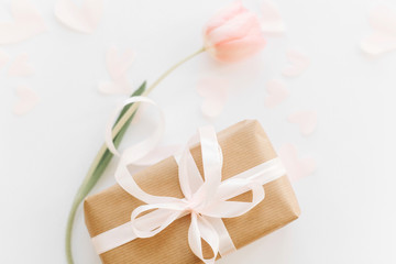 Gift box with ribbon and pink tulip flat lay on white background, space for text. Stylish soft spring image. Happy womens day. Greeting card mockup. Happy Mothers day. Romantic Valentines day