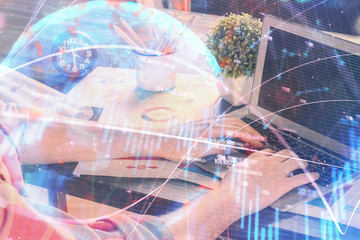 Double exposure of stock graph with businessman typing on computer in office on background. Concept of hard work.